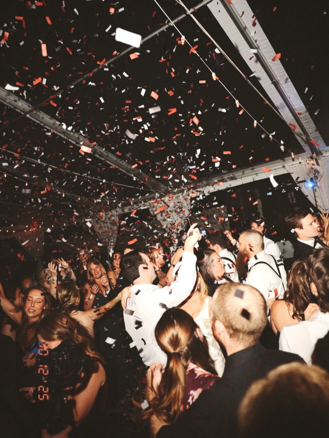 Packed function dancefloor with red and white confetti